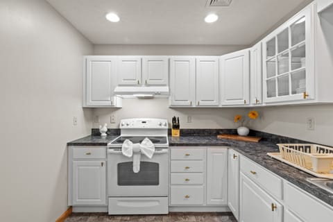 Fully stocked kitchen with white appliances, stainless sink, dishwasher, microwave, toaster, and coffee maker.
