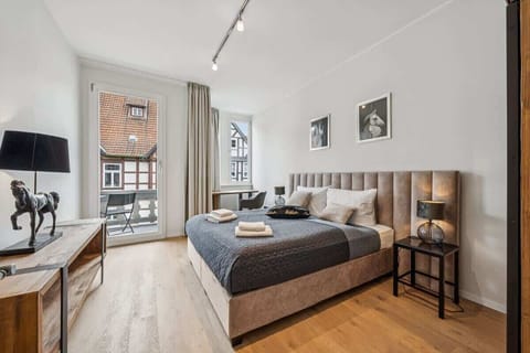 Helles Schlafzimmer mit Boxspringbett, Schreibtisch und Balkon – Blick auf die Altstadt inklusive.