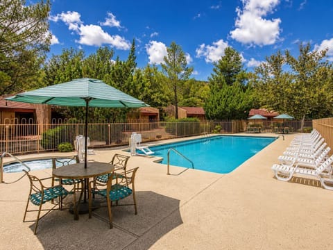 A bright and inviting outdoor pool area surrounded by lush greenery and lounge chairs, perfect for family fun and relaxation in the Sedona sun.