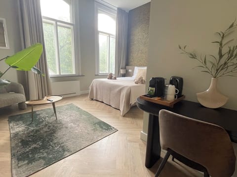 Spacious bedroom at Bed en Koffie Stationsstraat with king-size bed, TV, and serene garden views.