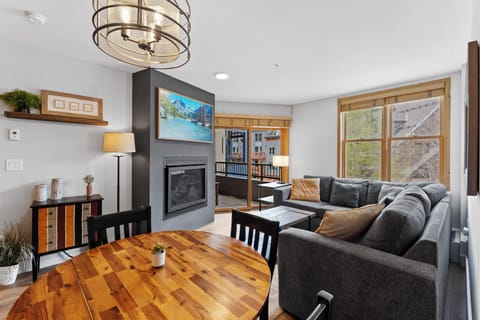 Cozy up in your modern living room with plush sectional seating, warming fireplace, and mountain views through picture windows.