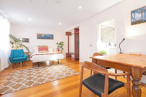 A seamless studio layout blends rest, dining, and work in one thoughtfully designed area, complete with a queen bed, dining spot, and a cosy armchair for quiet moments.