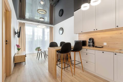 A modern kitchen with bar stools at a wooden island, sleek white cabinetry, and warm lighting.