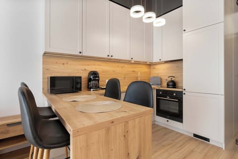 A modern kitchen with white cabinets, black chairs, and a wooden island in the center.