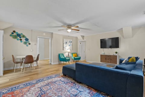 Spacious living room with a sofa, two arm chairs, a table with chairs, and a SmartTV