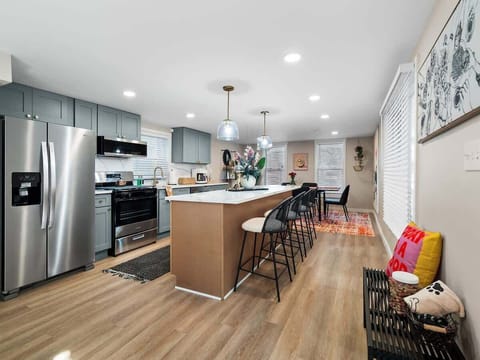 Bright open kitchen w/ large island seating, stainless steel appliances & stylish pendant lighting.