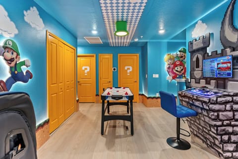 Welcome to our lively game room, featuring playful blue walls with iconic characters that energize the space. Cheerful yellow doors enhance the ambiance, and the sleek gaming station promises hours of fun for guests of all ages.