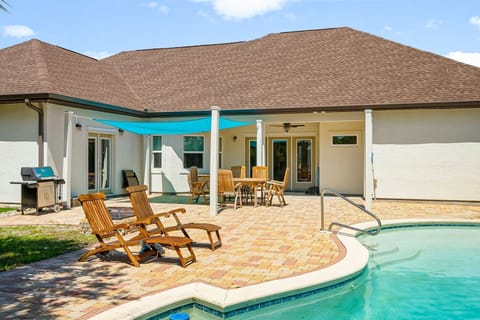 Relax and unwind in the private backyard oasis featuring a sparkling pool, sun loungers, and lush tropical landscaping.