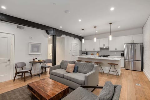 Living room with open-concept design featuring a white brick wall, Smart TV, and comfy sleeper sofa—ideal for lounging or accommodating extra guests.