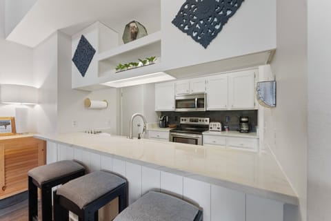 A full kitchen featuring stainless steel appliances, and breakfast bar seating 3.