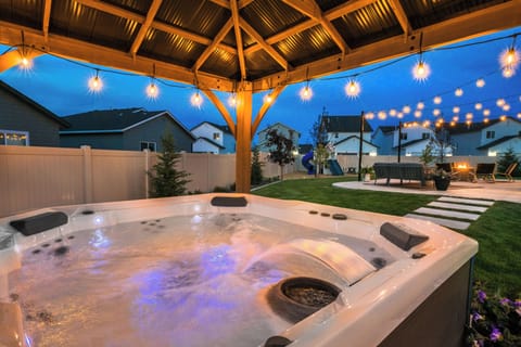 Evenings are made magical under the lights—soak in the private mineral hot tub while the kids play on the slide and the fire pit glows nearby. Connection, comfort, and a bit of luxury await in this backyard retreat.