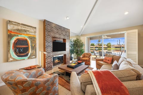 Cozy, modern space with fireplace, vibrant décor, and sliding doors opening to a scenic lakefront patio.