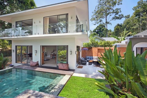Outdoor saltwater swimming pool shaded by trees and lush surrounding garden.