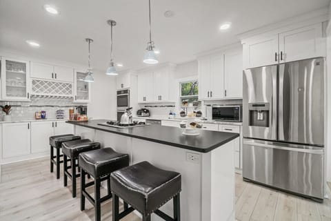 Kitchen | Modern White Cabinetry, Large Island with Seating, and Stainless Steel Appliances