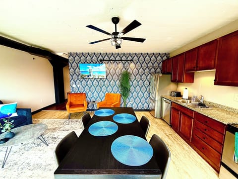 Dining Meets Design
A dark wood dining table with blue-accented placemats complements the artistic wallpaper and warm wood tones throughout.