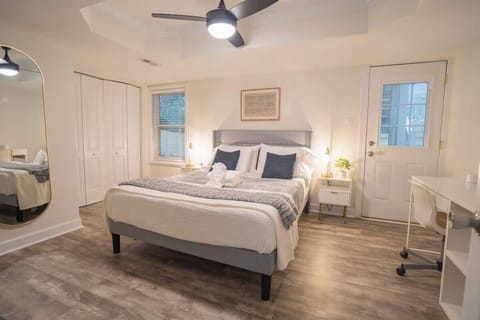 Bedroom equipped with queen bed, desk, chair, mirror, ceiling fan, nightstands, walk-in closer, and door to outdoor patio