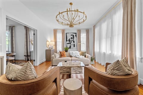 "Bright, elegant living space with designer touches, cozy seating, and floor-to-ceiling windows for a warm, welcoming vibe."