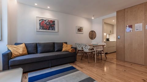 A stylish open-plan space with warm wooden floors, a cosy lounge, and a dining area designed for relaxed city stays. #LivingRoom #OpenPlanLiving #ModernApartment #CityBreak #LisbonStay #Portugal #PT #Lisbon