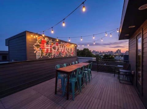 Vibrant rooftop featuring a colorful “HOWDY!” mural, string lights, ample seating, and beautiful downtown skyline views
