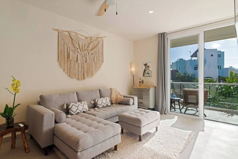 Inviting living room with a couch for an extra guest and a private balcony to enjoy Caribbean Sea views, complete with air conditioning and a ceiling fan for optimal comfort.
