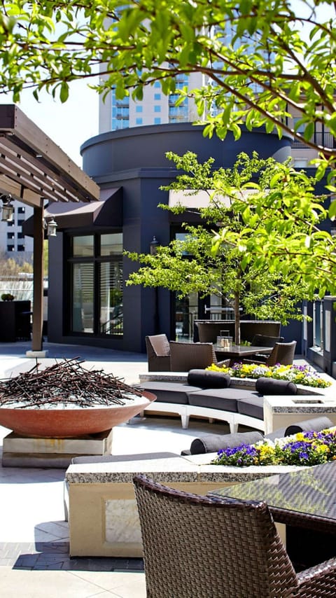 Outdoor lounge with firepit, greenery, and seating.