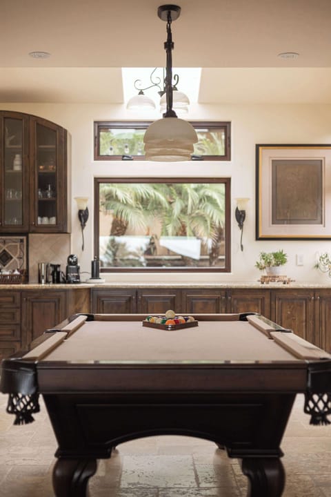 Stylish game room with pool table and tropical window views.