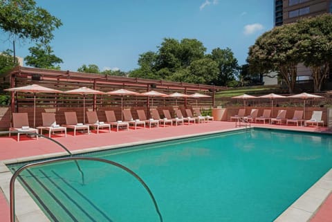 Large outdoor pool with pink chairs and umbrellas