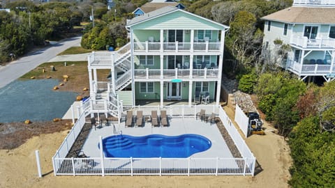 Aerial view of a three-story beach house with private pool, multiple decks, and waterfront access in a coastal neighborhood.
