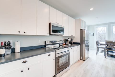Natural light fills the fully equipped kitchen and the dining set on the right, creating a warm and inviting atmosphere.