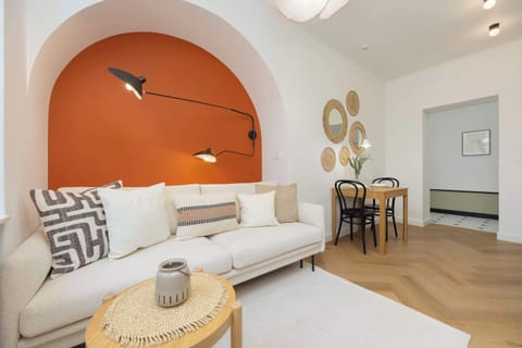 A living room with an arched orange accent wall, a white couch, rattan coffee table, and wall art, blending modern and boho decor.