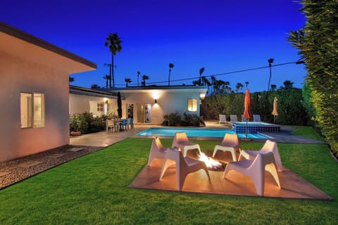 Resort-style backyard with fire pit lounge, pool, and evening lighting