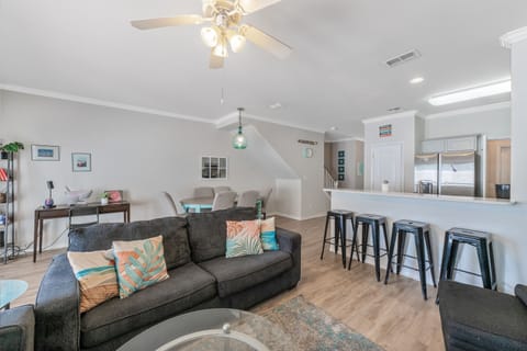Relax in your bright, open living space where modern comfort meets coastal charm with tropical-inspired pillows and stylish bar seating.