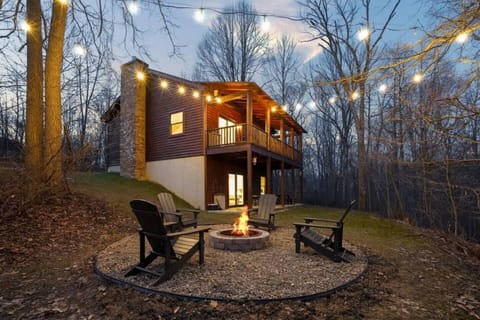 A cozy firepit setup surrounded by Adirondack chairs and string lights, perfect for relaxing evenings in the woods.