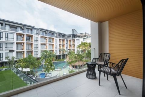 Private balcony with a table and two chairs overlooking the pool and garden.