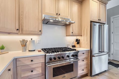 This luxury kitchen features a spacious center island with elegant seating, modern stainless steel appliances, and warm wood cabinetry. Stylish pendant lighting completes this inviting, gourmet space.