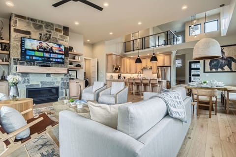 This open-concept living area features a stunning stone fireplace, cozy loft, and a modern kitchen. With high ceilings and plush seating, it’s the perfect space for group gatherings.