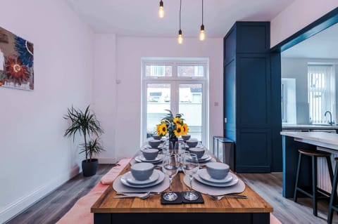Bright and welcoming dining space featuring a beautifully set wooden table, modern pendant lighting, and stylish décor. Natural light fills the room, creating the perfect place to enjoy breakfast, share meals, or relax with friends and family.