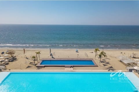 Shared oceanfront pool overlooking the sandy beach & blue horizon, perfect for a refreshing swim by the sea