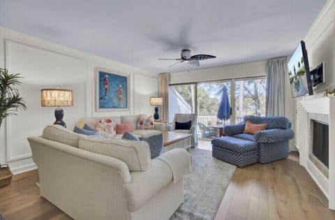 Your bright, coastal-style retreat features plush seating, a cozy fireplace, and French doors opening to a private balcony overlooking natural greenery—perfect for unwinding after a day of adventure.