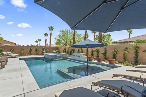 Resort-style pool w/ sun loungers & shaded seating, perfect for cooling off under blue skies