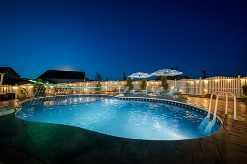 Stunning pool area illuminated against the evening sky, complete with lounge chairs and umbrellas for perfect relaxation.