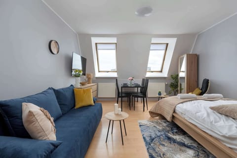 A bright room with two single beds, a blue sofa, and a small round coffee table with decorative elements. 
