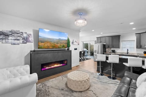 The beautiful living room includes plenty of comfortable seating, a large Smart TV, and a stunning gas fireplace.