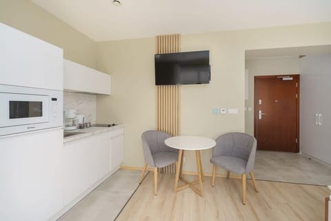 A small, modern kitchen with white cabinets, a microwave, and an electric stove. The space is functional and well-organized.