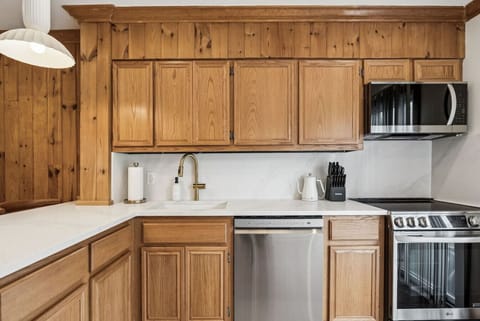 The open kitchen features a breakfast bar, sleek quartz counters and modern LG appliances