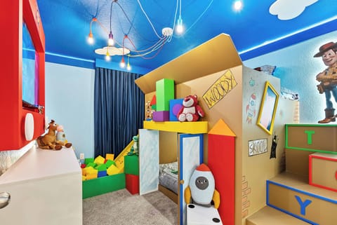 This vibrant playroom, with its whimsical design, colorful building blocks, and charming playhouse, fosters creativity. The playful blue ceiling and fun lighting create an energizing atmosphere for kids to explore and enjoy.