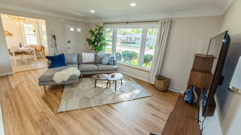Relaxing sitting room with large bay windows with views of mature trees.