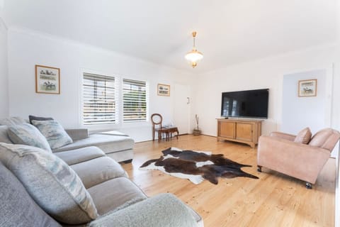 Stretch out in the bright living area, with timber floors, soft seating, and relaxed coastal character.