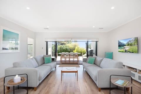 Settle in for movie nights or morning coffee, framed by garden views through wide glass doors that open to the deck.