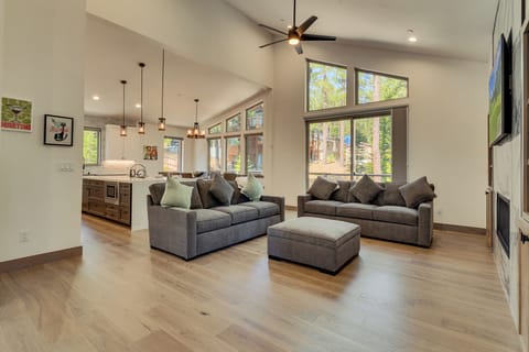 Open living area with sofas and an ottoman, connected to the kitchen and dining space